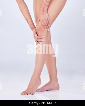 I should get this seen to. an unrecognizable woman holding her injured knee against a grey background Stock Photo