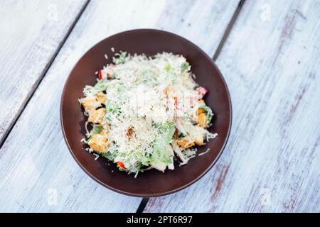 Top view Classical Caesar salad with roasted chiken, quail eggs, lettuce leaves, becon, parmesan slices and cherry tomatoes on the white plate on the Stock Photo