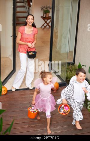Halloween is about fun. two happy kids leaving a house on Halloween with buckets of treats Stock Photo