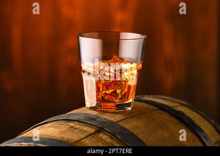 Glass of whisky with ice on the top of barrel Stock Photo