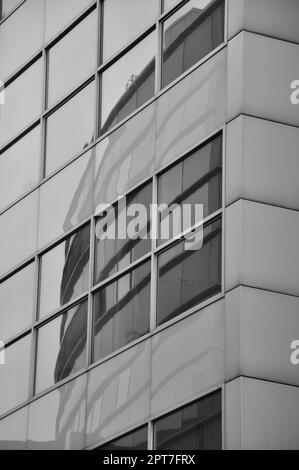 Vertical grayscale shot of buildings reflection in window pane in Media Harbor. Dusseldorf, Germany. Stock Photo