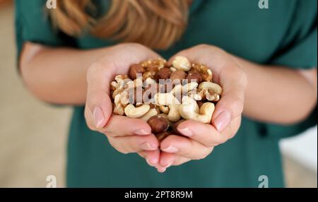 Woman showing abundance and variety of nuts mix of dried fruits in her hands Stock Photo