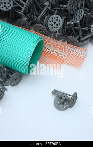 A set of construction items for the insulation of walls. Plastic dowels, a roll of mesh for the insulation of facades and a corner profile with a grid Stock Photo