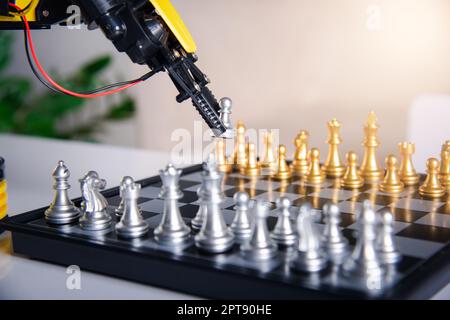 Closeup yellow robot arm playing move chess on chessboard, STEM education E-learning, Technology science robot education concept Stock Photo
