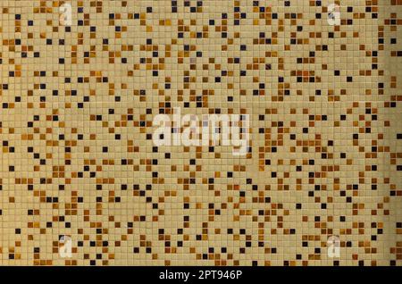 The texture of the wall, decorated with a mosaic of various small square tiles. Abstract pattern of ceramic tiles on the wall Stock Photo