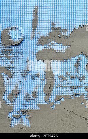 The texture of the wall, covered with gray foam polystyrene plates, covered with a blue reinforcing mesh and covered with a mixture for gluing it. Sta Stock Photo
