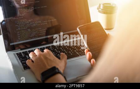 Software developer hands typing data coding programming javascript with laptop computer and mobile phone, Programmer woman looking smartphone program Stock Photo