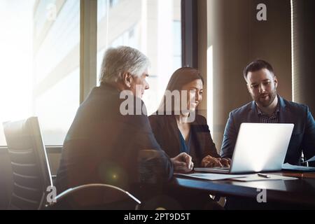 Working on their latest project. three businesspeople working together in the boardroom. Stock Photo