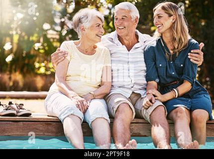 Time to make some summer memories. a happy young woman spending quality time with her elderly parents at the pool. Stock Photo