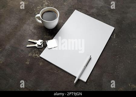 Blank letterhead, coffee cup, key and pen on concrete background. Copy space for text. Stock Photo