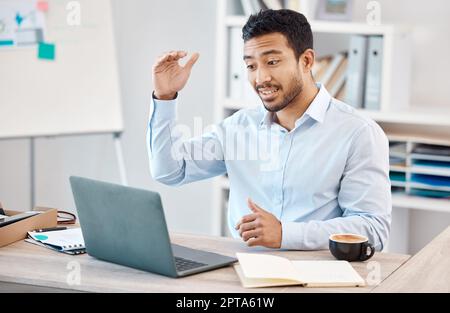 Man with laptop at desk on video call for work, via web in office with coffee and gesture with hand. Young man at table in home office, with computer Stock Photo