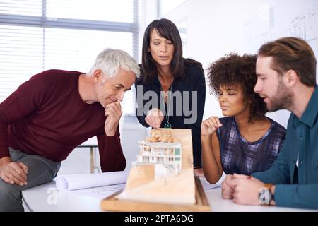 Giving their design some serious. a group of architects working together on building plans Stock Photo