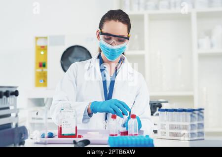 It takes long but has to get done. an unrecognizable young female scientist wearing protective fave gear while conducting experiments inside of a labo Stock Photo