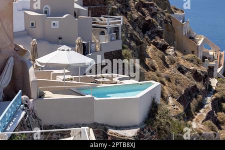 Oia, Santorini, Greece - July 3, 2021: Whitewashed houses with terraces and pools and a beautiful view in Oia on Santorini island, Greece Stock Photo