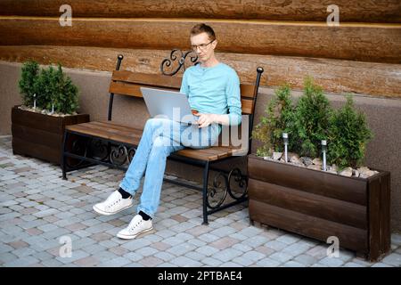 Middle aged man makes online order using laptop outdoors Stock Photo