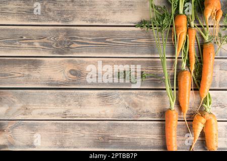 Vertical line of fresh ripe carrots on faded wooden table, top view. Raw vegetables arranged in order. Organic food or healthy diet concept. Location Stock Photo