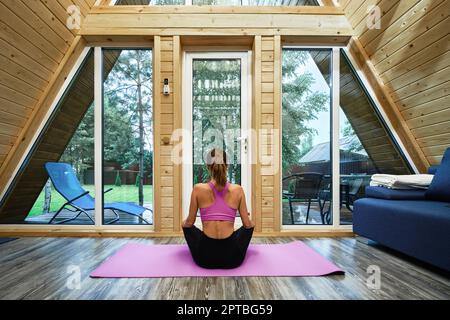 Woman practicing yoga lotus position in forest house Stock Photo