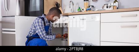 African American Plumber Man Fixing Blocked Kitchen Sink Stock Photo