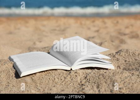 Open book on sandy beach near sea Stock Photo