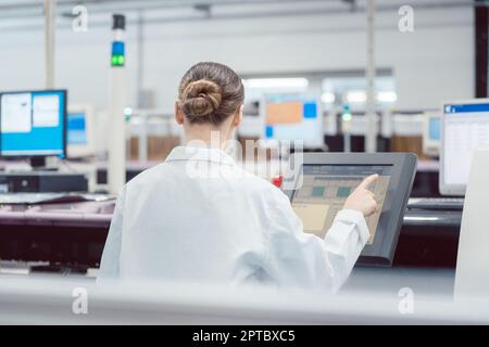 Woman on control compute of assembly line in electronics factory Stock Photo