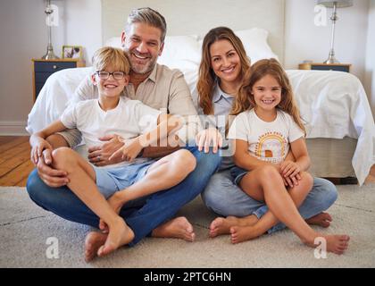 Portrait family, children smile and parents with love for kids on floor in bedroom of house together. Boy and girl siblings happy bonding with mother Stock Photo