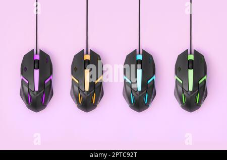 Several computer mice hang on a pastel pink background. The concept of cooperative computer video games, the use of auto-clicker and pay-per-click pla Stock Photo