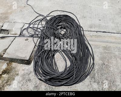 Black rolled electric cable on a road surface background Stock Photo