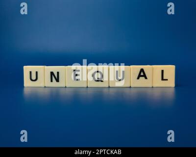 Toy word with the word UNEQUAL on blue background Stock Photo