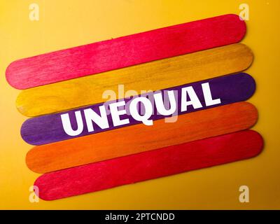 Colored wooden stick with the word UNEQUAL on yellow background Stock Photo