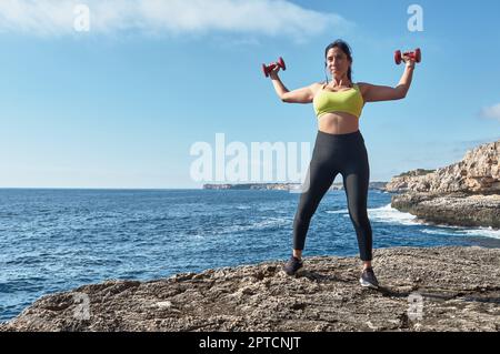 Latin woman, middle-aged, wearing sportswear, training, doing physical exercises, plank, sit-ups, climber's step, burning calories, keeping fit, outdo Stock Photo