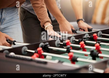 Hands, foosball and table with friends playing a game together indoors for fun or recreation. Football, fun and leisure with a friend group together t Stock Photo