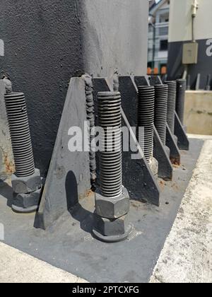 Bolts and nuts on the cement base. Several gray double bolts are firmly fixed to a steel column to a concrete base. Close focus and select an object Stock Photo