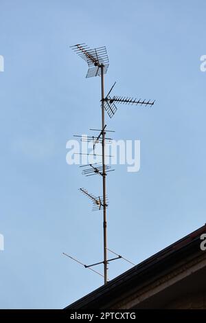 Antennas on a metal mast on an old roof Stock Photo