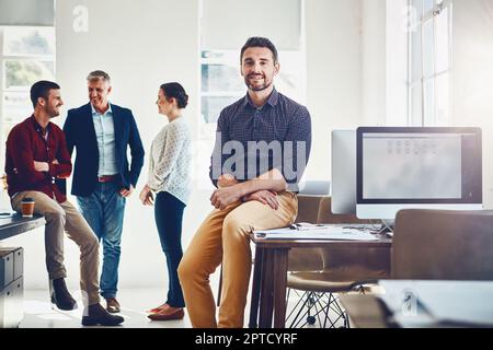 My team is made of individuals who play well together. Portrait of a young man with his colleagues having a discussion in the background. Stock Photo