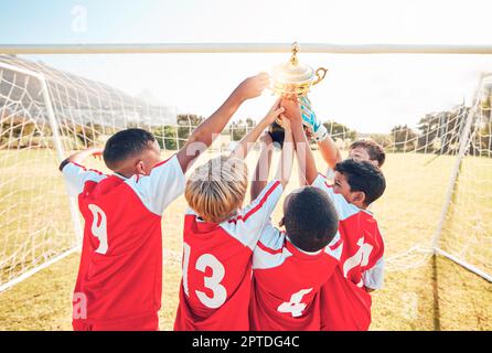 Children, winner and team soccer with trophy celebrating victory, achievement or match on the field. Kids in celebration for teamwork, sports and foot Stock Photo