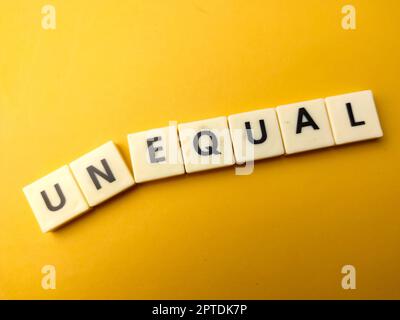 Toy word with the word UNEQUAL on yellow background Stock Photo