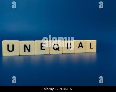 Toy word with the word UNEQUAL on blue background Stock Photo