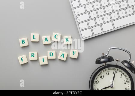 Black friday text, computer keyboard and alarm clock on the gray background. Top view. Stock Photo