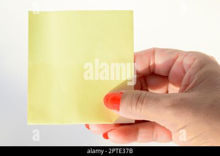 Woman's hand with painted nails holding blank letter paper on pure white background. Stock Photo
