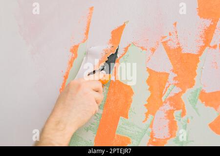 Man smoothes wall surface with a wall grinder. Male grind a white plaster wall - renovation and redecoration Stock Photo