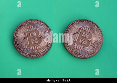 Two chocolate products in the form of physical bitcoins lie on a green plastic background. Model of the crypto currency in the edible form Stock Photo