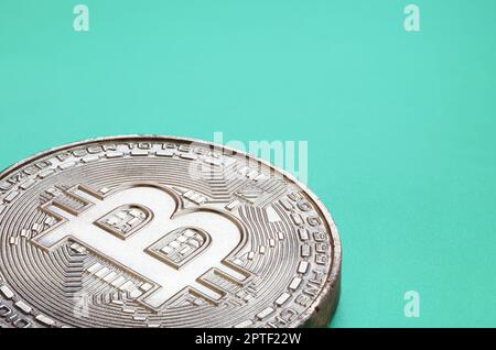 Chocolate product in the form of physical bitcoin lies on a green plastic background. Model of the crypto currency in the edible form Stock Photo