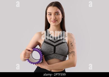 Sporty young woman with foam roller on light background Stock Photo