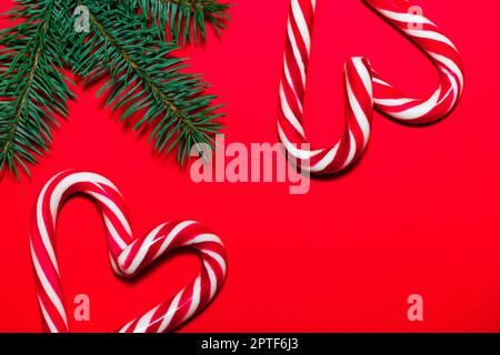 Lollipop hearts on red surface with Christmas tree branches. Christmas and New Year greeting card Stock Photo