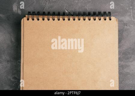 Opened brown kraft paper notebook on spring on gray concrete surface. Top view. Copy space Stock Photo