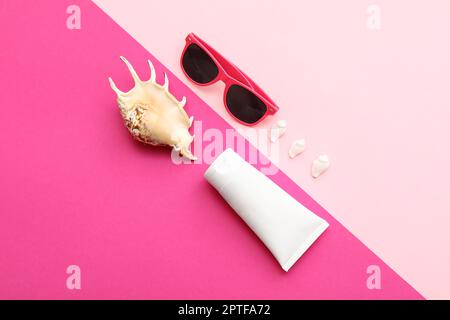 Composition with sunglasses, seashells and sunscreen on pink background Stock Photo