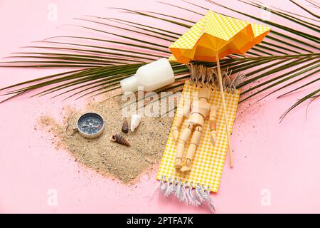 Composition with seashells, compass, palm leaf and wooden mannequin lying on beach towel against pink background Stock Photo