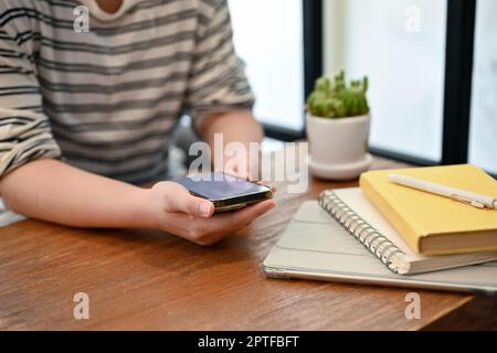 Cropped image of an Asian girl using her smartphone at a cafe. people and technology concept Stock Photo