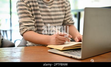 Cropped image of an Asian female college student doing her homework at the coffee shop. Stock Photo