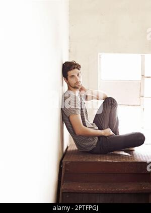 Casual and boyish style. Young man sitting and contemplating his future on a stairwell Stock Photo Alamy